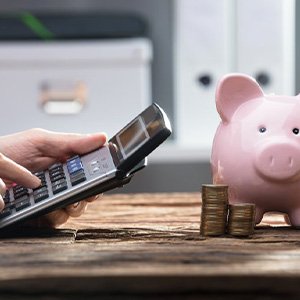 Patient using a calculator with piggybank and coins nearby