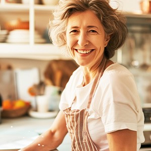 Woman smiling while in the kitchen washing dishes