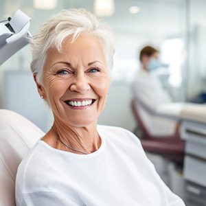 Older woman smiling in the dentist’s chair with dental implants