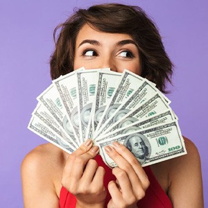 Woman holding a fan of Benjamins in front of her face