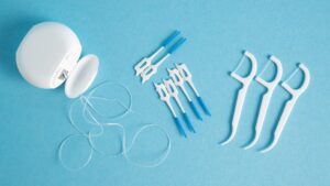 Bird's eye view of 3 types of floss on light blue surface